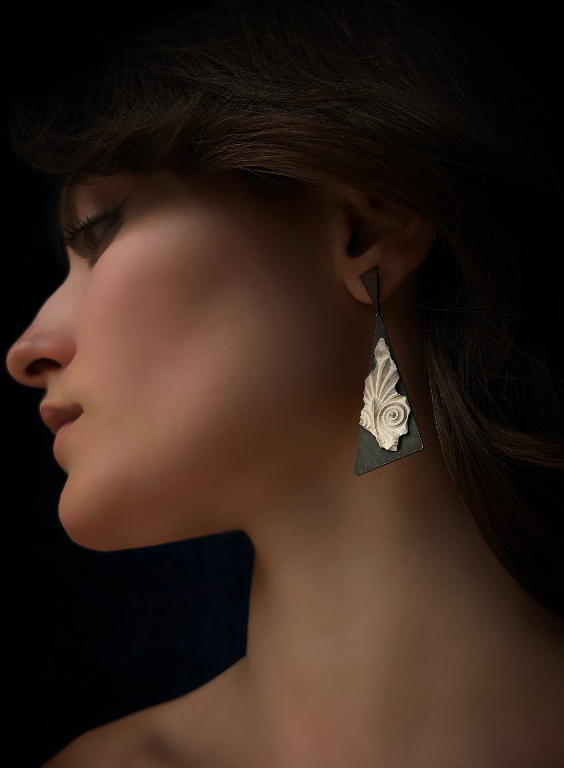 Close-up of a woman wearing a decorative earring against a dark background