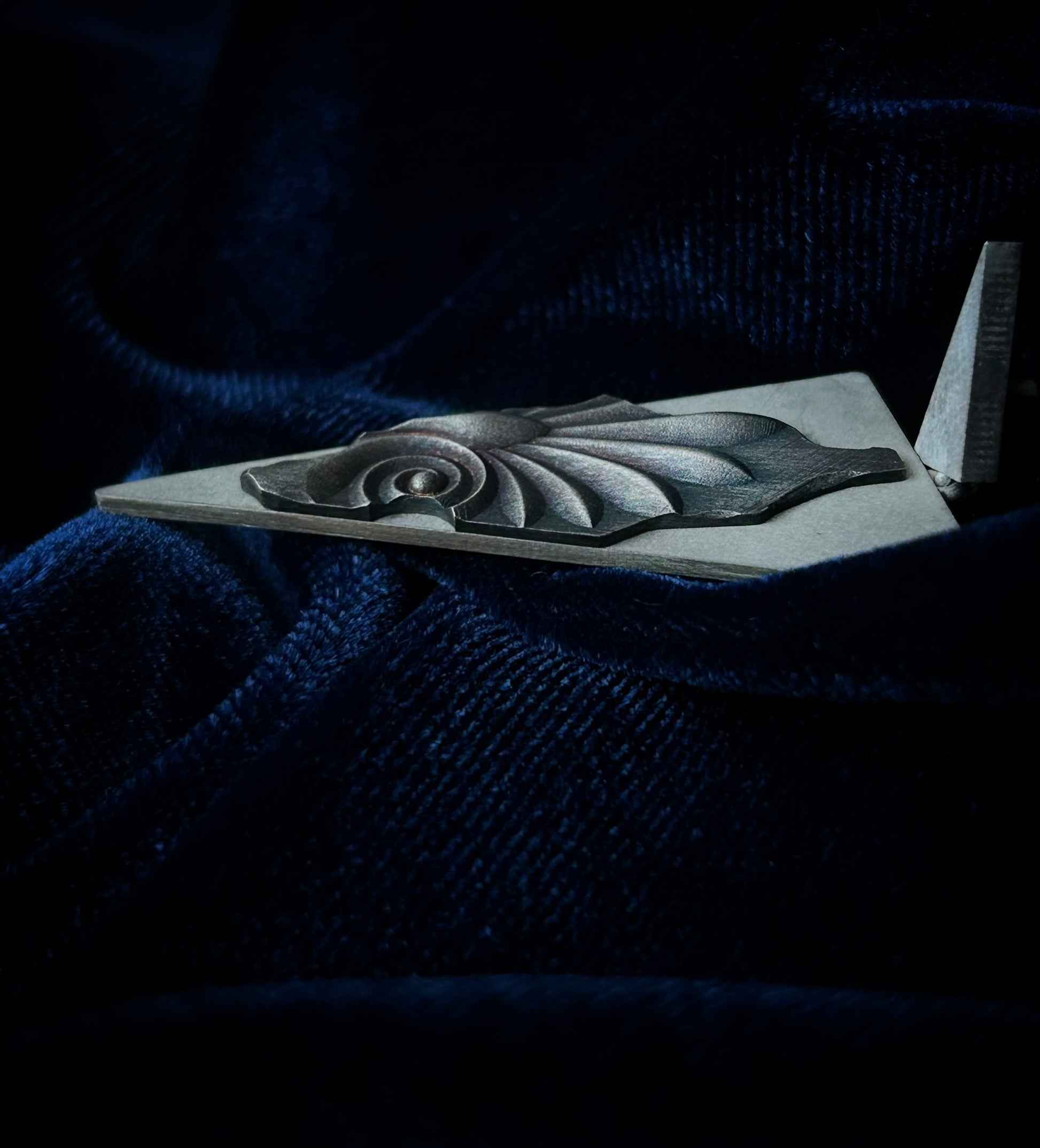 Decorative silver object on a dark blue fabric background