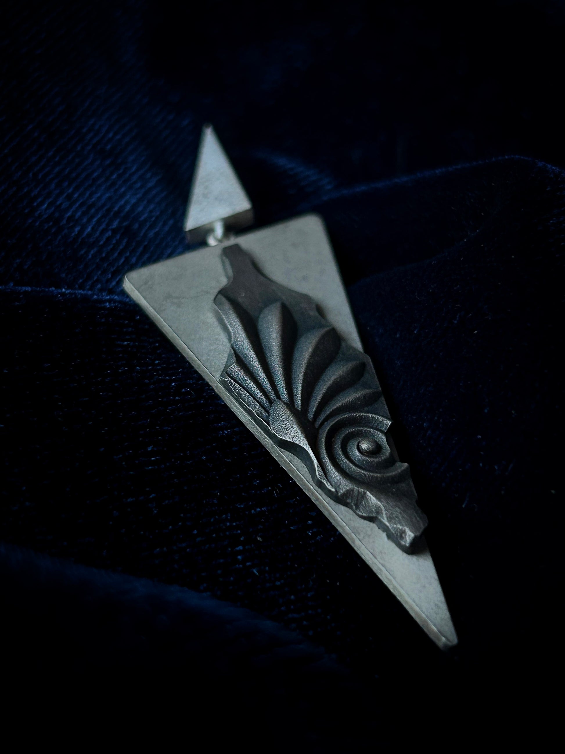 Silver pendant with abstract design on a dark background