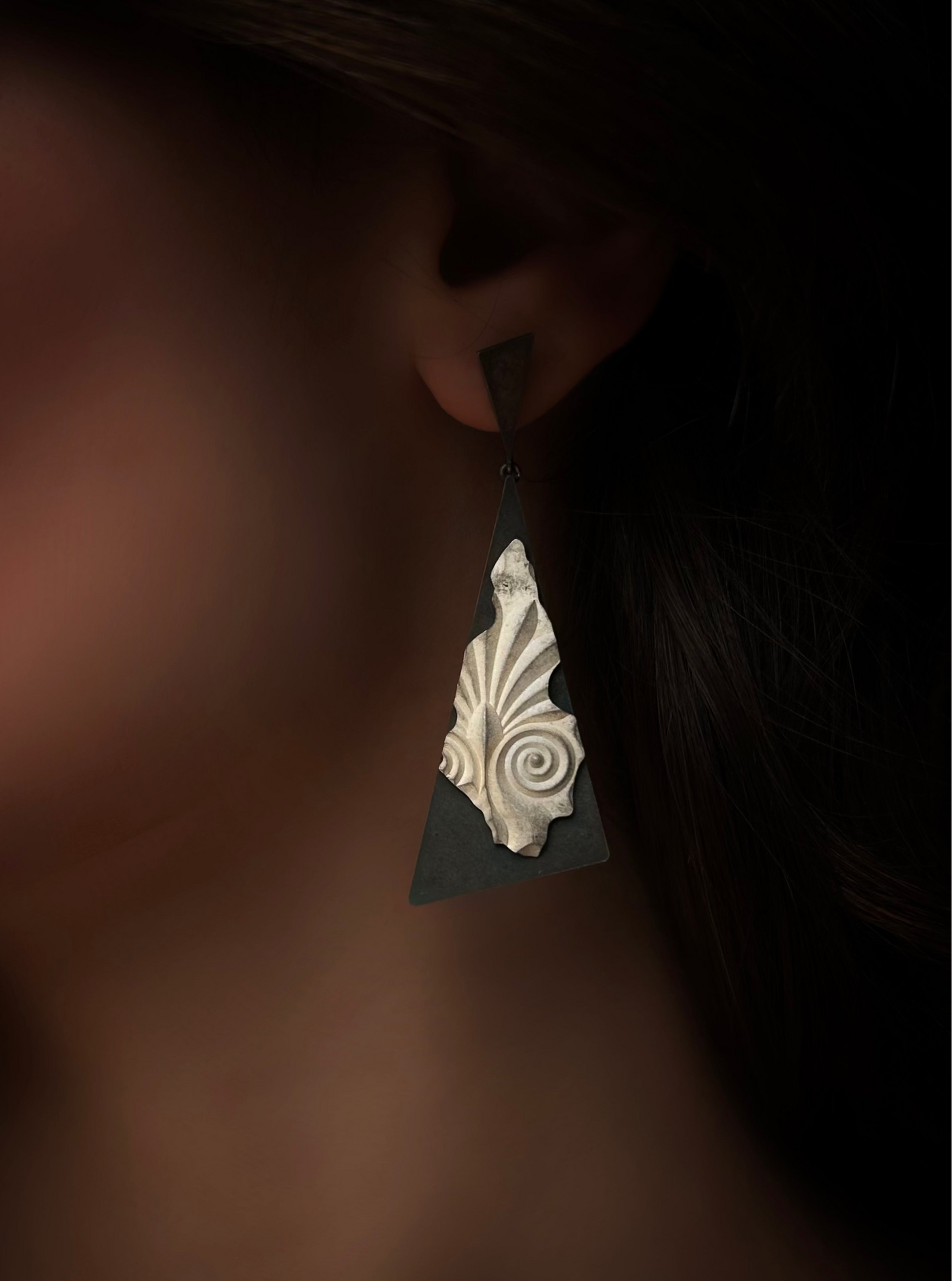Close-up of an ear wearing a decorative triangle-shaped earring.