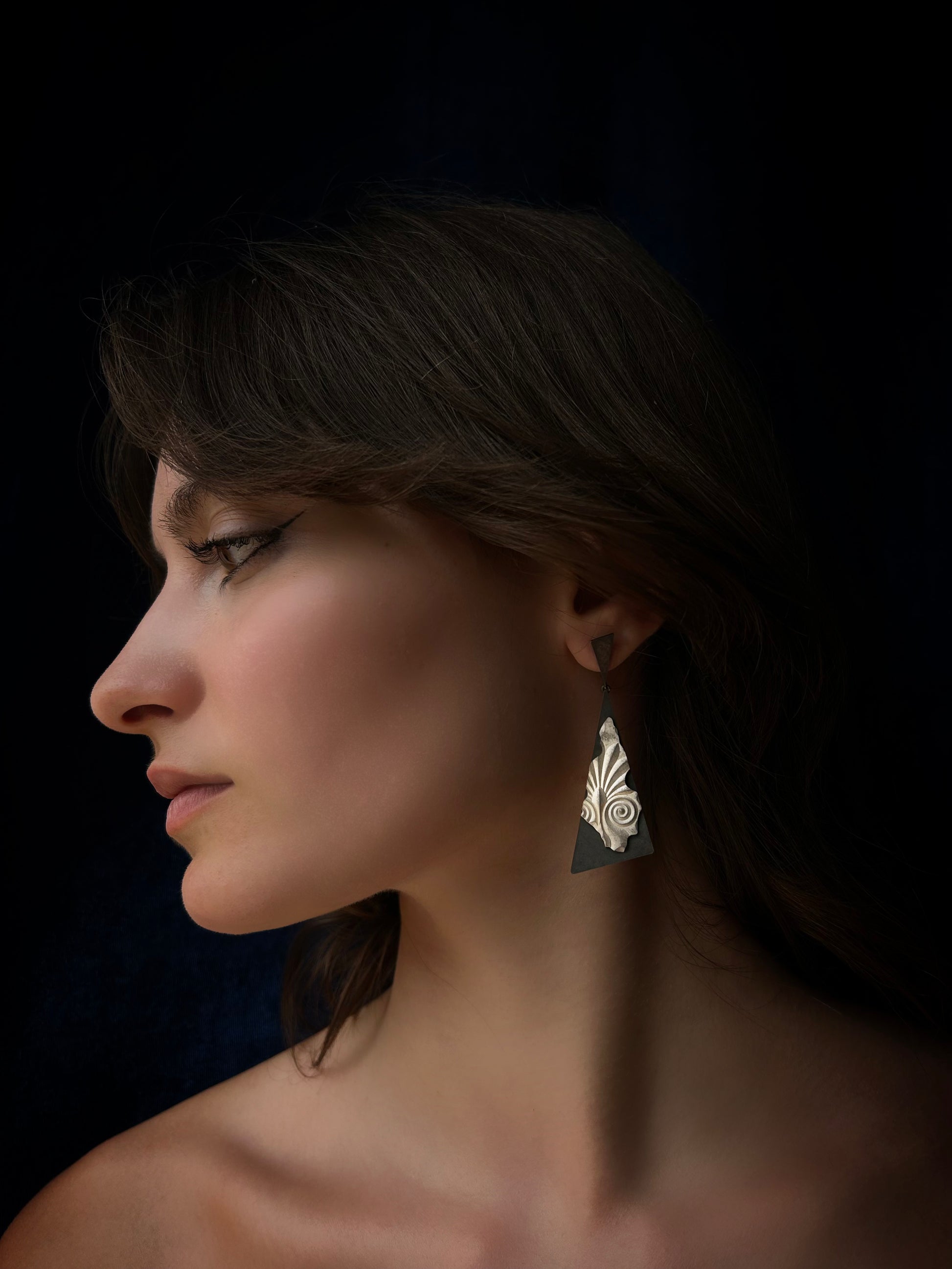 Close-up of a woman wearing an earring against a dark background
