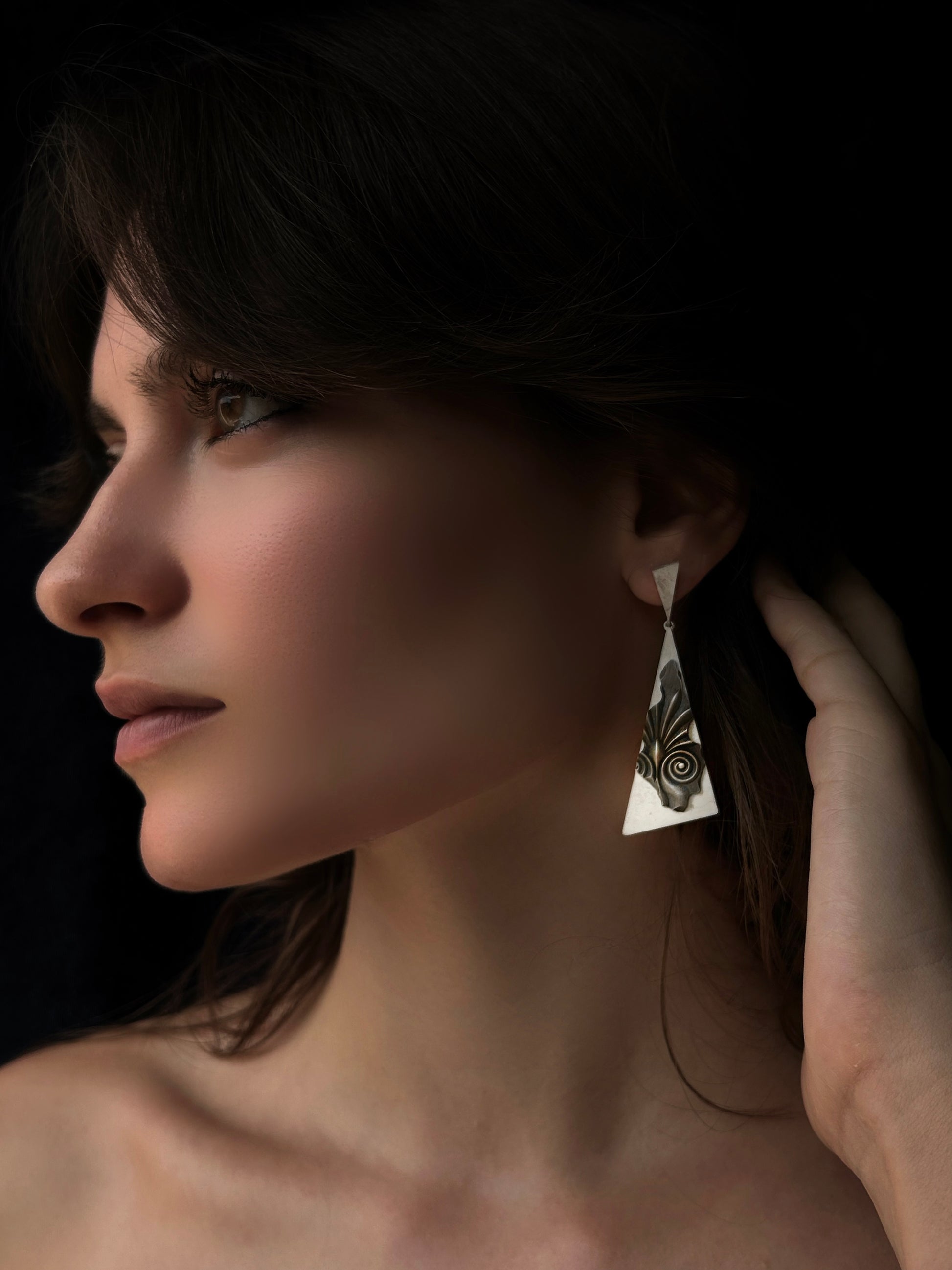 Close-up of a woman wearing a silver earring with a dark background