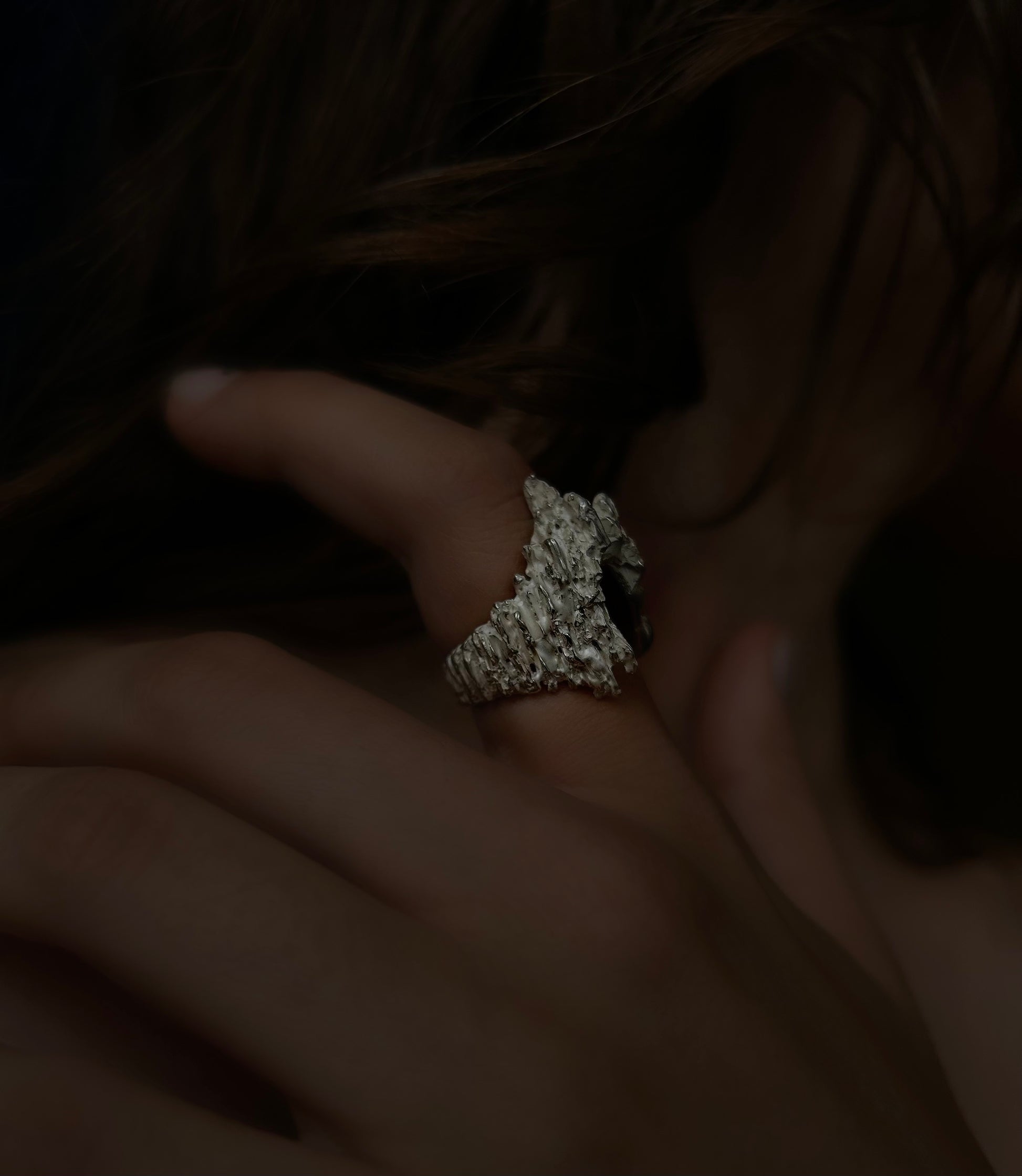 Close-up of a hand wearing a ring with a textured stone.