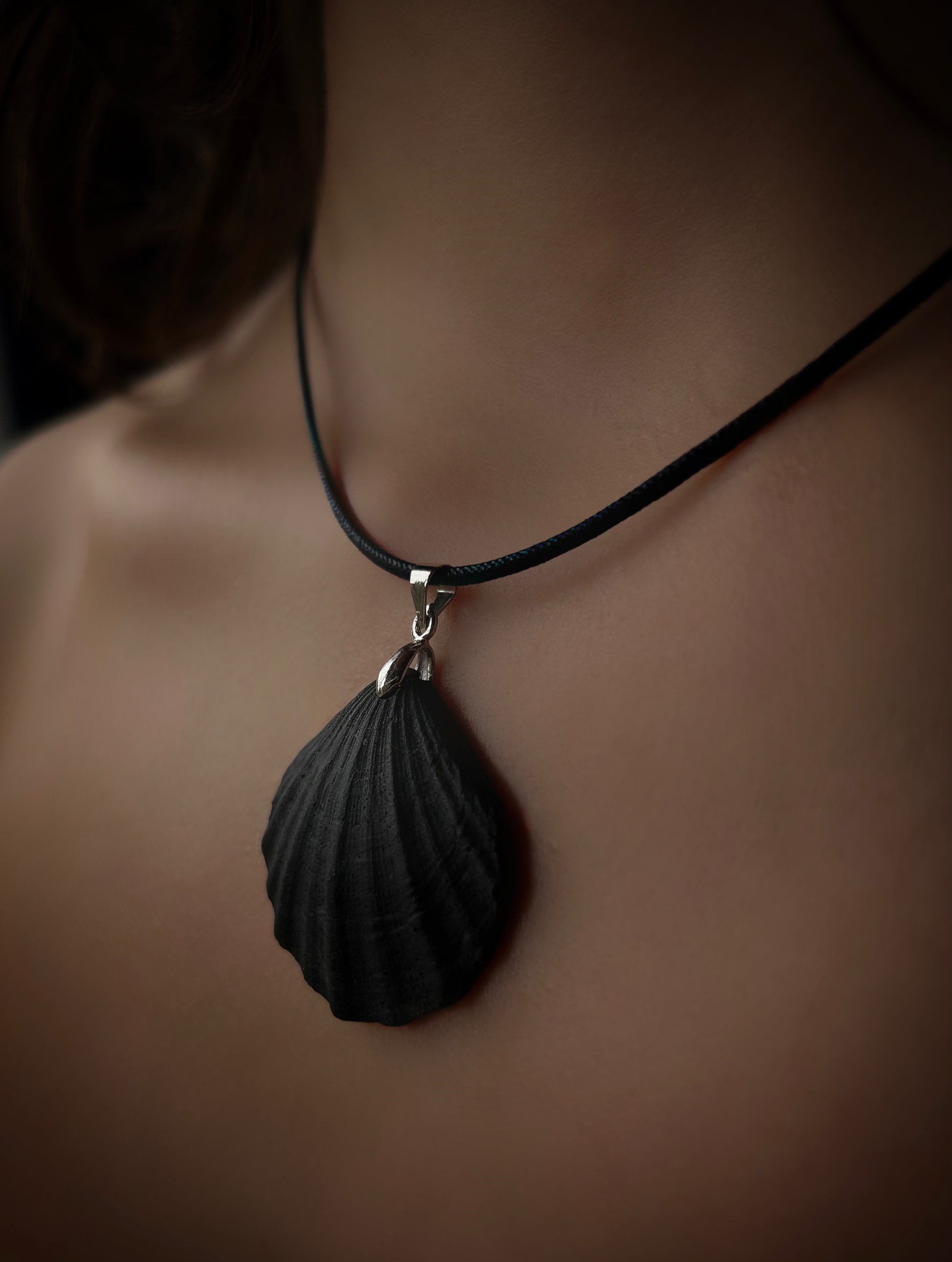 Black shell pendant necklace on a mannequin with a blurred background