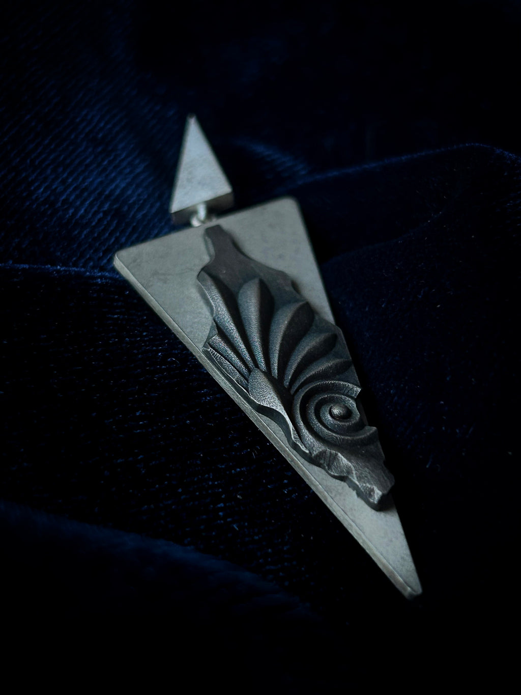 Silver pendant with abstract design on a dark background
