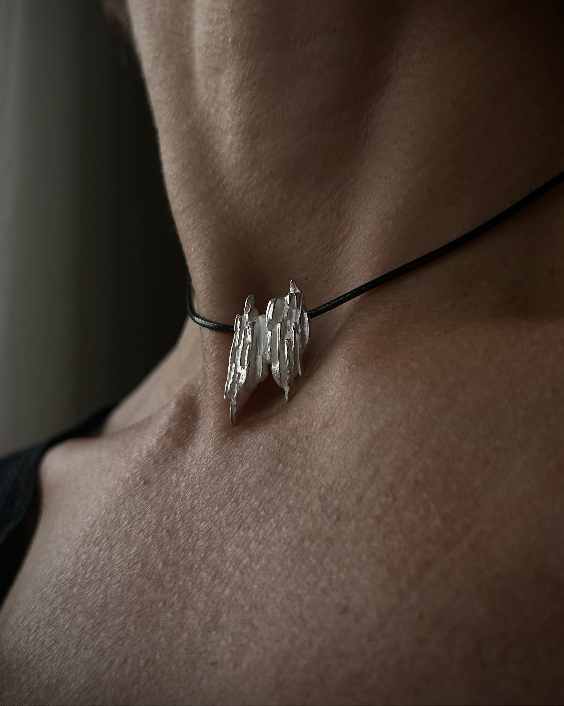 Close-up of a person wearing a silver necklace with a unique pendant.