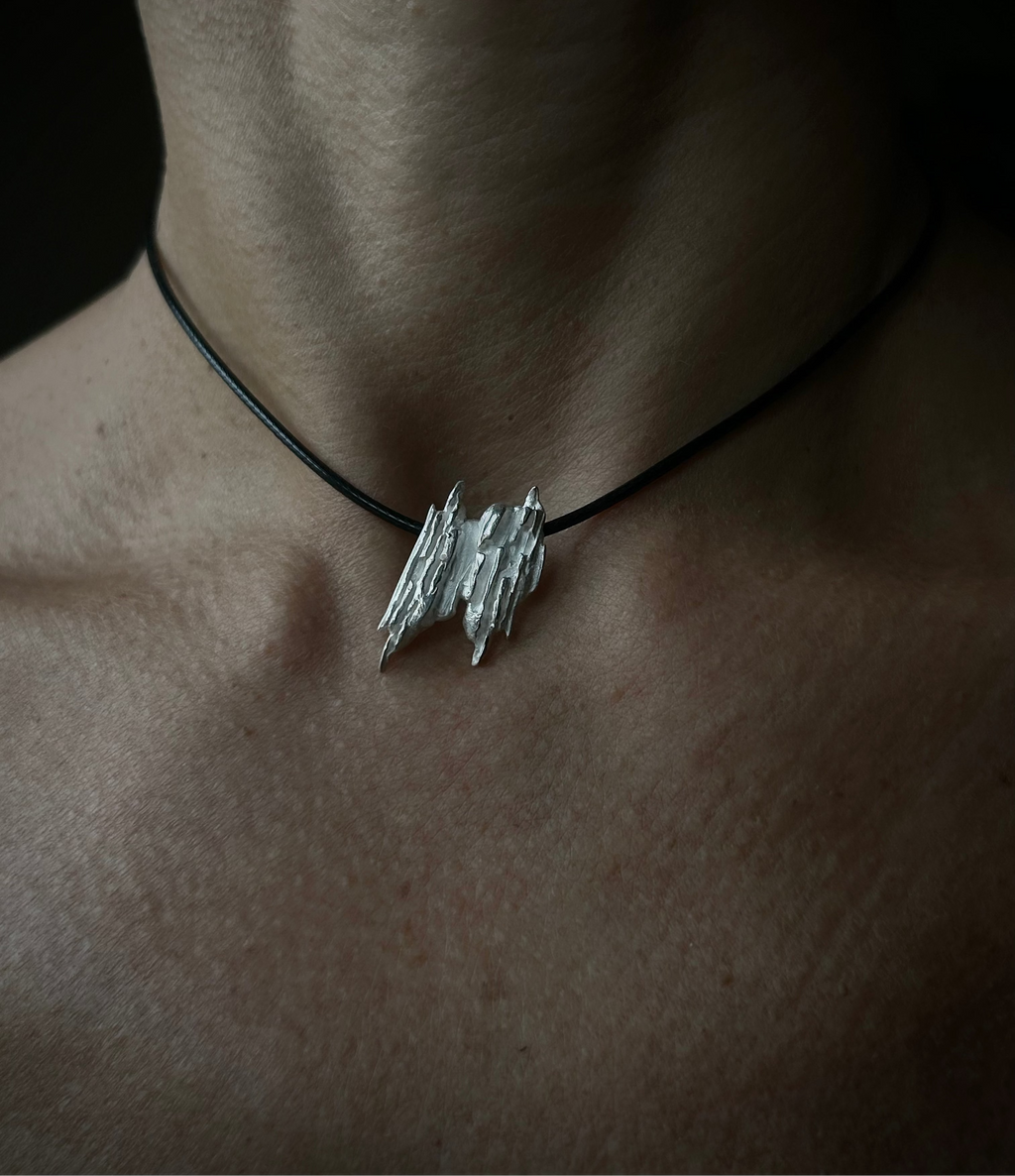 Necklace with a unique pendant on a person's neck against a dark background