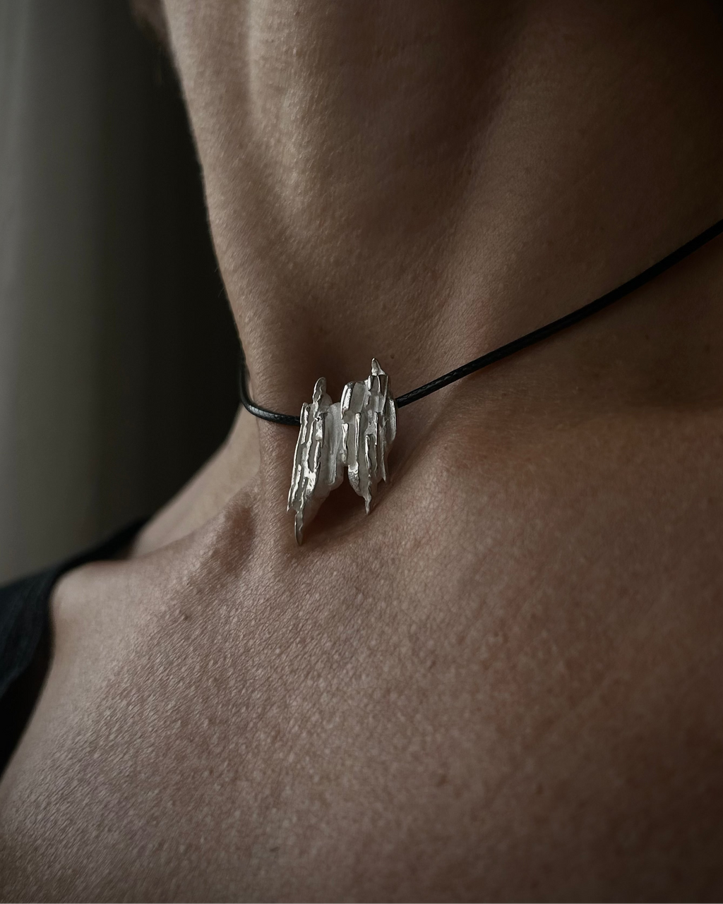 Close-up of a person wearing a silver necklace with a unique pendant.